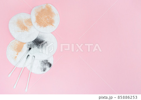 Used cotton pads and cotton swabs. Used cosmetic pad after removing make-up. Pink background. Place for text. Copy space. Flat lay. Dirty 85886253