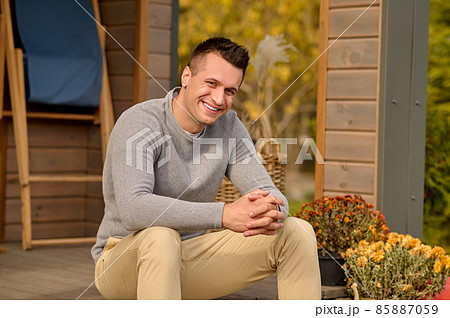 Man sitting near house looking at camera Man sitting near house looking at camera 85887059