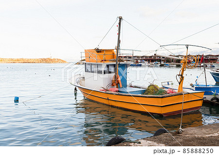Small yellow fishing boat is moored in fishing harbor 85888250