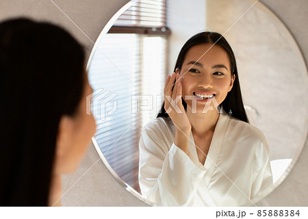 Young beautiful korean lady using moisturising face cream Young beautiful korean lady using moisturising face cream 85888384