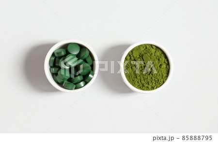 Chlorella and spirulina. Spirulina pills and chlorella green powder on a white background. Mineral food additive. Top view, flat lay. 85888795
