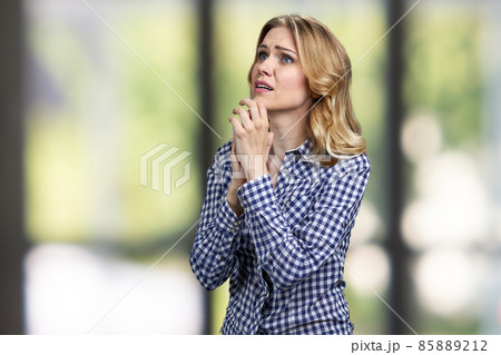 Desperate stressed worried young woman is praying on blur interior background. 85889212