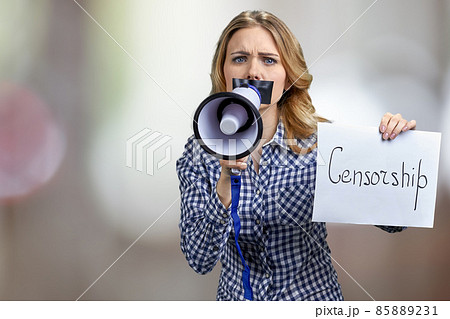 Censored woman unable to speak standing against blurred bokeh background. Censored woman unable to speak standing against blurred bokeh background. 85889231