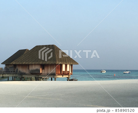 モルディブのエメラルドグリーンの海に浮かぶロッジと白い砂浜 85890520