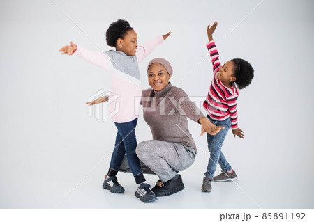 Two cheerful sisters playing with mother in studio 85891192