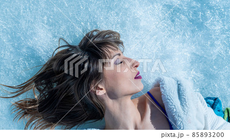 Close-up portrait of a caucasian woman lying on the snow.  85893200
