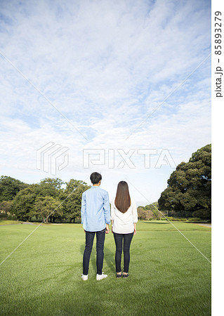 若い日本人カップルの後ろ姿、夏の朝、公園の芝生 85893279