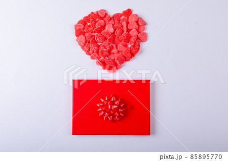 Red heart shape candies over gift box around copy space on white background 85895770