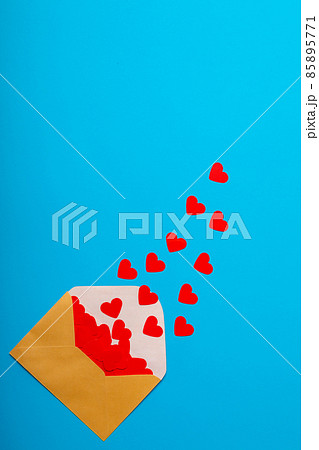 Overhead view of open beige envelope with red heart shapes by copy space over blue background Overhead view of open beige envelope with red heart shapes by copy space over blue background 85895771
