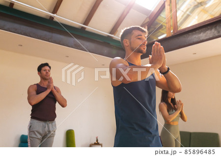 Multiracial men and woman practicing yoga pose with hands clasped and eyes closed in yoga studio Multiracial men and woman practicing yoga pose with hands clasped and eyes closed in yoga studio 85896485