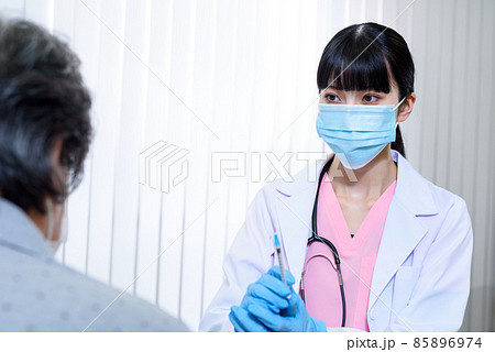 診察室で女性高齢者にワクチン接種の注射をするスクラブを着てマスクをした女性医療従事者 外来 診察 診察室で女性高齢者にワクチン接種の注射をするスクラブを着てマスクをした女性医療従事者 外来 診察 85896974