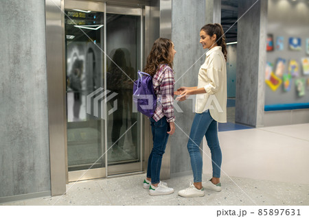 Woman and a girl talking before the closed elevator doors Woman and a girl talking before the closed elevator doors 85897631