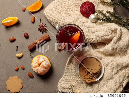 Mulled wine or glegg with oranges and spices, on the table with ginger cookies, tangerines and attributes of the new year. Top view on grey background Mulled wine or glegg with oranges and spices, on the table with ginger cookies, tangerines and attributes of the new year. Top view on grey background 85901046