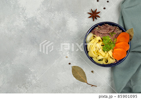 Lagman, homemade noodles, boiled meat and vegetables. Top view on a gray background, horizontal with space 85901095