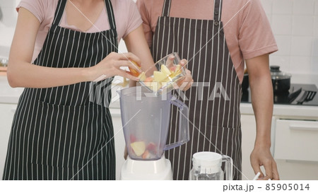 couple husband and wife making fresh smoothie in kitchen together at home couple husband and wife making fresh smoothie in kitchen together at home 85905014