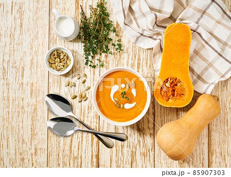 Bowl with pumpkin soup or butternut squash soup on a white wooden table, top view. 85907303
