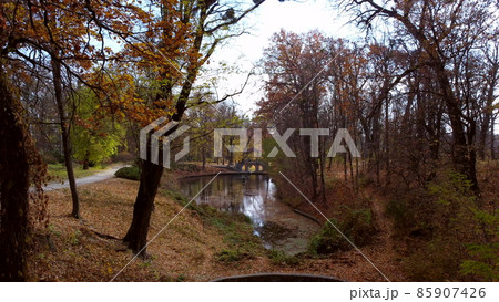 Aerial drone view flight through tree branches in park with lakes, architecture Aerial drone view flight through tree branches in park with lakes, architecture 85907426