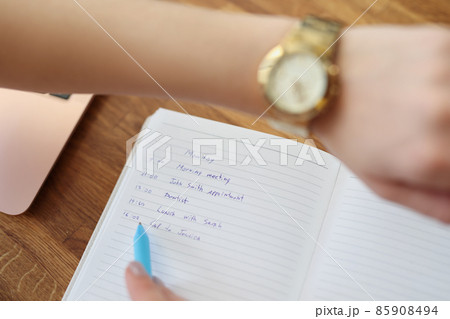 Woman write down plan for day, look at wristwatch to check time Woman write down plan for day, look at wristwatch to check time 85908494