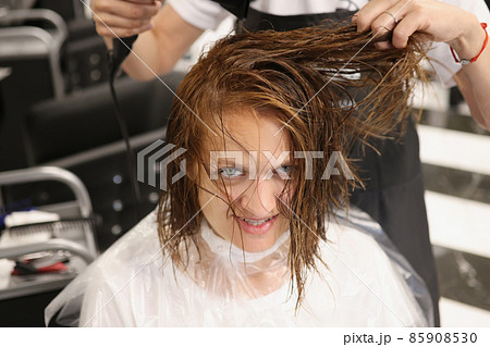 Hairdresser using hairdryer for treatment with hair, dry wet hair after beauty procedure 85908530