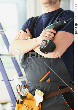 Professional carpenter man in uniform with electric drill, ready to start renovation 85908544
