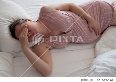 Pregnant caucasian woman lying on bedbeing tired 85909238