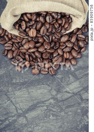 Heap of dark roasted fragrant coffee beans in jute bag. Copy space for text 85909756