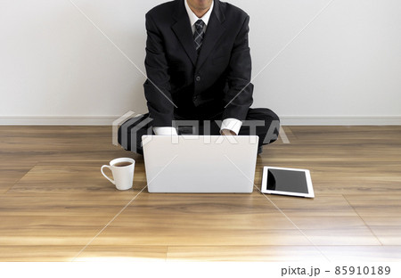 床に座ってノートパソコンを操作しているスーツ姿の男性 85910189