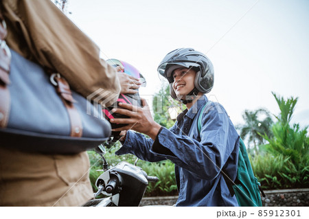 Man gives a helmet to someone while picking him Man gives a helmet to someone while picking him 85912301