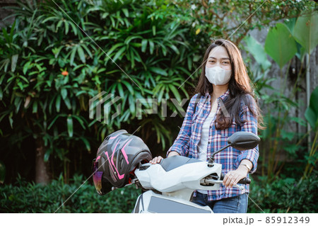 Attractive girl standing wearing mask beside motorcycle with copyspace 85912349