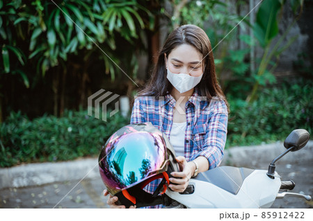 Woman with mask takes helmet before road riding motorbike 85912422