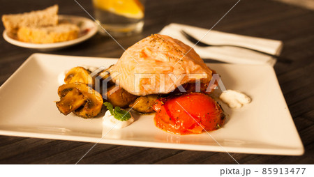 simmered slice of salmon with tomato spinon and coconut sauce on a white plate 85913477