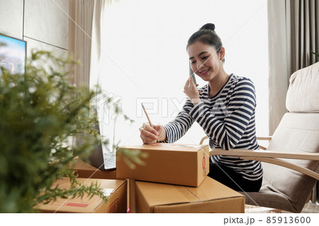 Business Start up SME concept. Young startup entrepreneur small business owner working at home, packaging and delivery situation. Women, owener of small business packing product in boxes Business Start up SME concept. Young startup entrepreneur small business owner working at home, packaging and delivery situation. Women, owener of small business packing product in boxes 85913600
