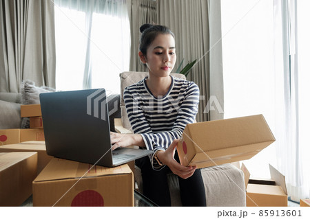 Business Start up SME concept. Young startup entrepreneur small business owner working at home, packaging and delivery situation. Women, owener of small business packing product in boxes Business Start up SME concept. Young startup entrepreneur small business owner working at home, packaging and delivery situation. Women, owener of small business packing product in boxes 85913601