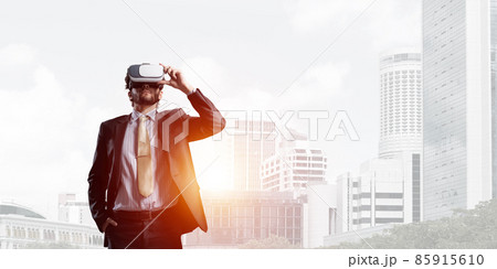 Handsome elegant businessman experiencing impressive virtual reality and business city at backdrop Handsome elegant businessman experiencing impressive virtual reality and business city at backdrop 85915610