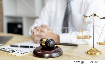 Male lawyer or judge sits and analyzes the case and decides the case with fairness, On the table were the scales of justice and the hammer of honest judgment, Concepts of Law and Legal services. 85916585