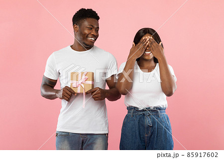 Happy black guy making surprise for his woman holding box Happy black guy making surprise for his woman holding box 85917602