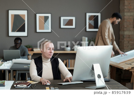 Serious mature female designer looking at computer screen Serious mature female designer looking at computer screen 85917639