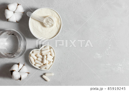 Collagen powder and pills on a gray background. A collagen supplement for beauty and health. Copy space, top view Collagen powder and pills on a gray background. A collagen supplement for beauty and health. Copy space, top view 85919245