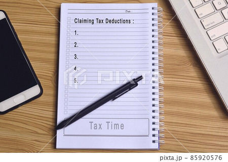 Text on notepad with laptop and smartphone on wooden table. Business and tax concept 85920576