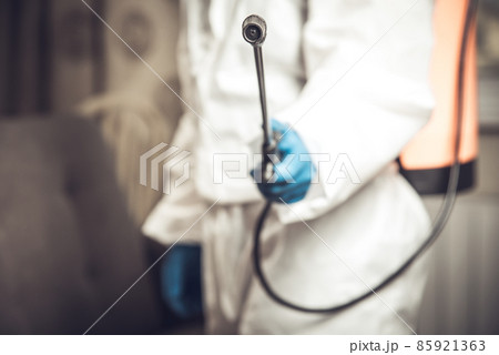 Spray gun with pesticides close-up. An exterminator in work clothes sprays pesticides from a spray bottle. Fight against insects in apartments and houses. Disinsection of premises 85921363