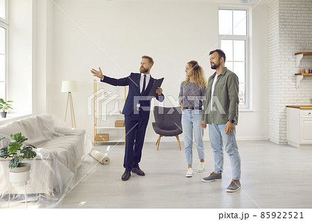 Realtor or real estate agent giving potential buyers or tenants tour about big house. Boyfriend and girlfriend or husband and wife who consider buying property looking at new modern spacious home 85922521