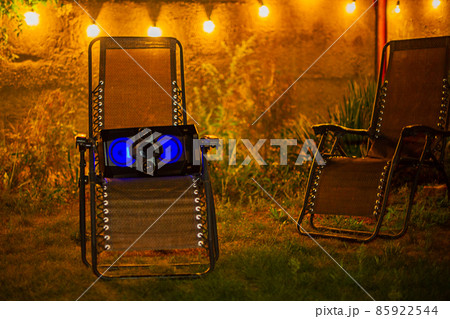 Two garden lounge chairs with a music speaker on one of the chairs. Evening rest with music. 85922544