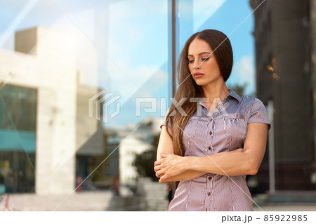 Business woman 35 years dressed stripe shirt with long hair standing near office building outdoor 85922985