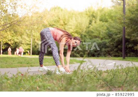 Fit woman warming up legs before running exercises standing running track in summer park Fit woman warming up legs before running exercises standing running track in summer park 85922995