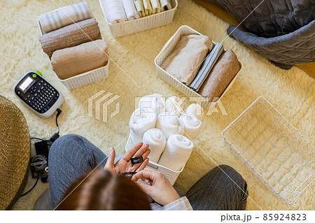 Woman hands neatly folded linens and towels use Marie Kondo method with sticky label tags Woman hands neatly folded linens and towels use Marie Kondo method with sticky label tags 85924823