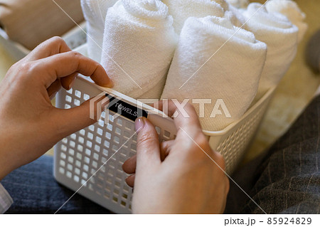 Woman hands neatly folded linens and towels use Marie Kondo method with sticky label tags 85924829