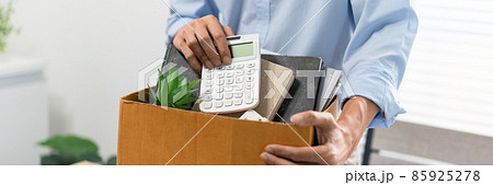 Resignation Concept The man in light blue shirt standing at the desk and putting the calculator and other stuff into the box Resignation Concept The man in light blue shirt standing at the desk and putting the calculator and other stuff into the box 85925278