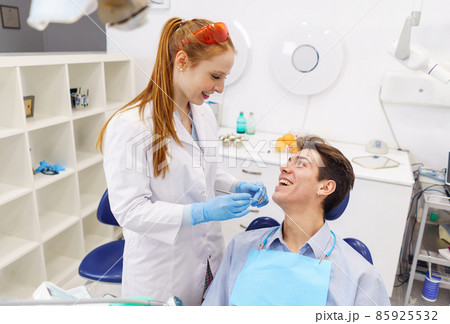 From above man and woman smiling and looking at each other during appointment in contemporary dentist office From above man and woman smiling and looking at each other during appointment in contemporary dentist office 85925532
