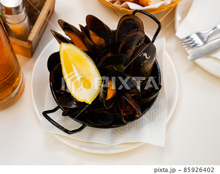 Steamed mussels with lemon wedge in metal serving pan Steamed mussels with lemon wedge in metal serving pan 85926402