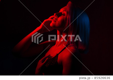 portrait of a blonde girl close-up in a room with red and blue light. portrait of a blonde girl close-up in a room with red and blue light. 85926636